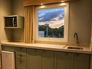 Una cocina con microondas integrado, una ventana con vista a un depósito de agua y un lavamanos con grifo moderno.