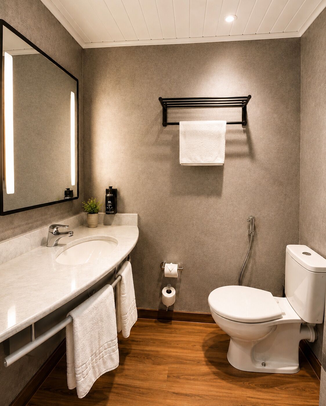 Un baño moderno con un espejo grande, un lavamanos, un inodoro y un perchero para toallas.