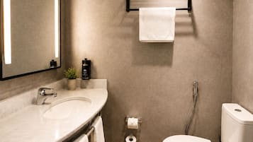 Un baño moderno con un espejo grande, un lavamanos, un inodoro y un perchero para toallas.