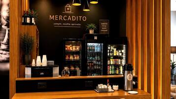 Zona de bar con la marca Mercadito, con mostrador de madera, asientos y dispensadores de bebidas.