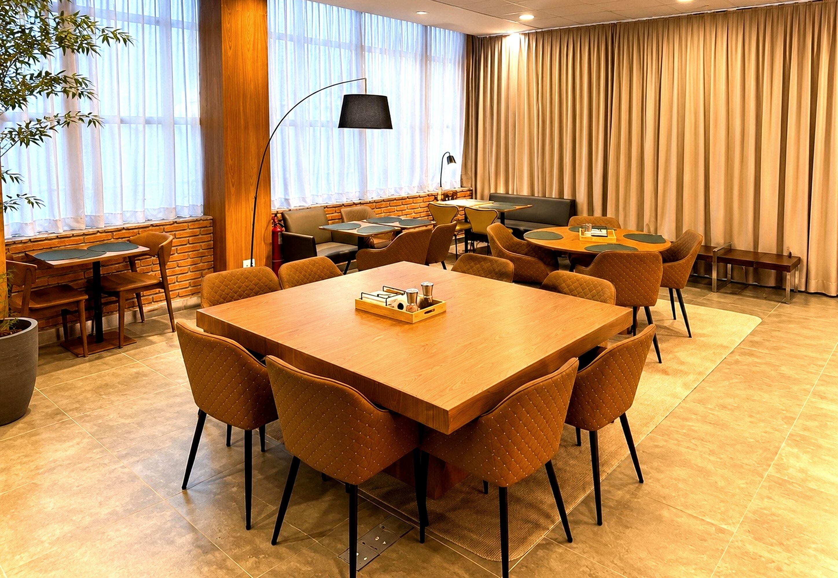 A conference room with a large wooden table, multiple chairs, a small side table, and a lamp.