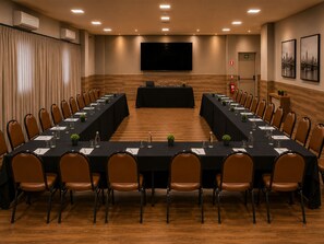 A conference room with a long table, chairs, a podium, and a large screen.