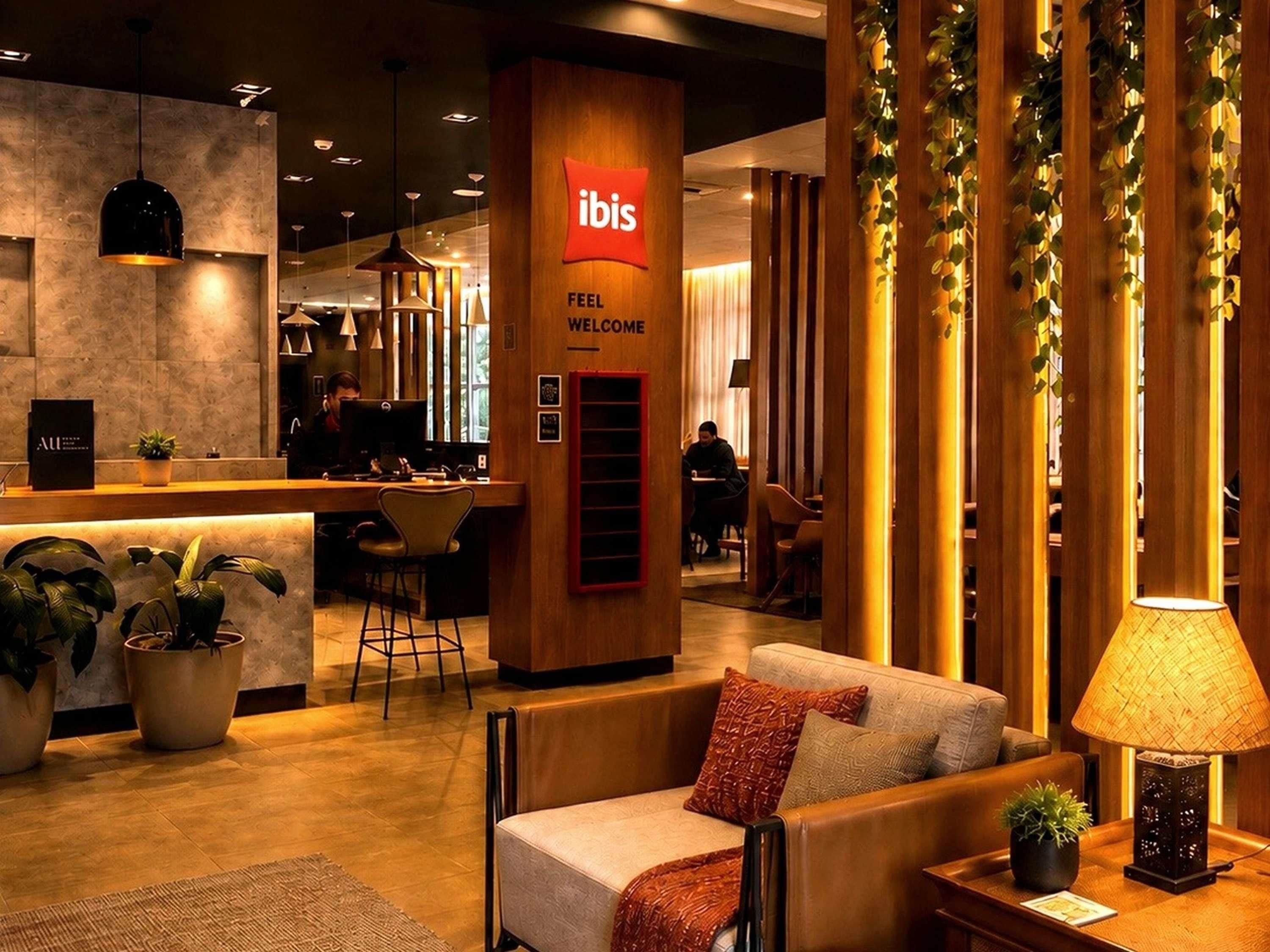 A modern hotel lobby with a reception desk, seating area, and a 'Feel Welcome' sign.