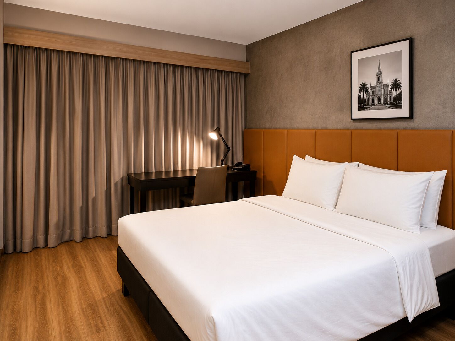 A hotel room with a bed, a desk, a chair, and a nightstand.