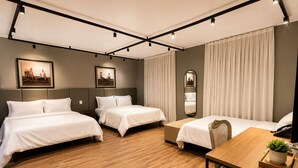A hotel room with two beds, a wooden floor, a desk with a plant, and a mirror on the wall. - ibis Catanduva (Catanduva)