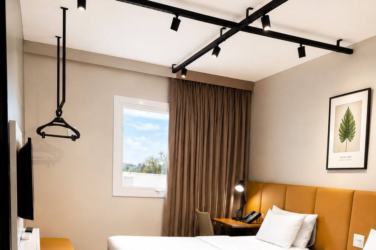 A hotel room with two beds, a desk, a chair, a TV, and a window with curtains.