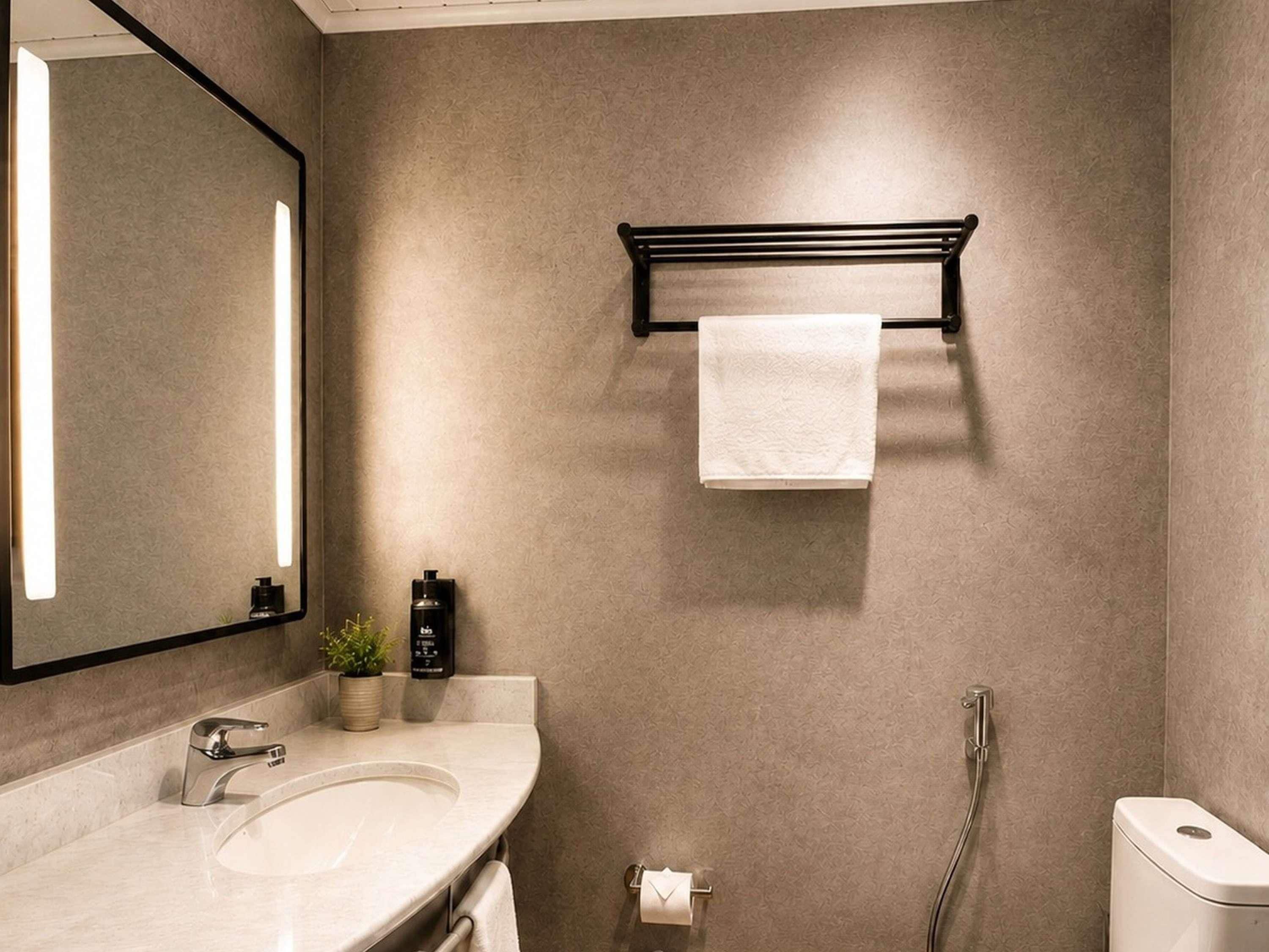 Une salle de bain équipée d’un lavabo, d’un miroir, d’un porte-serviettes et d’une douche.