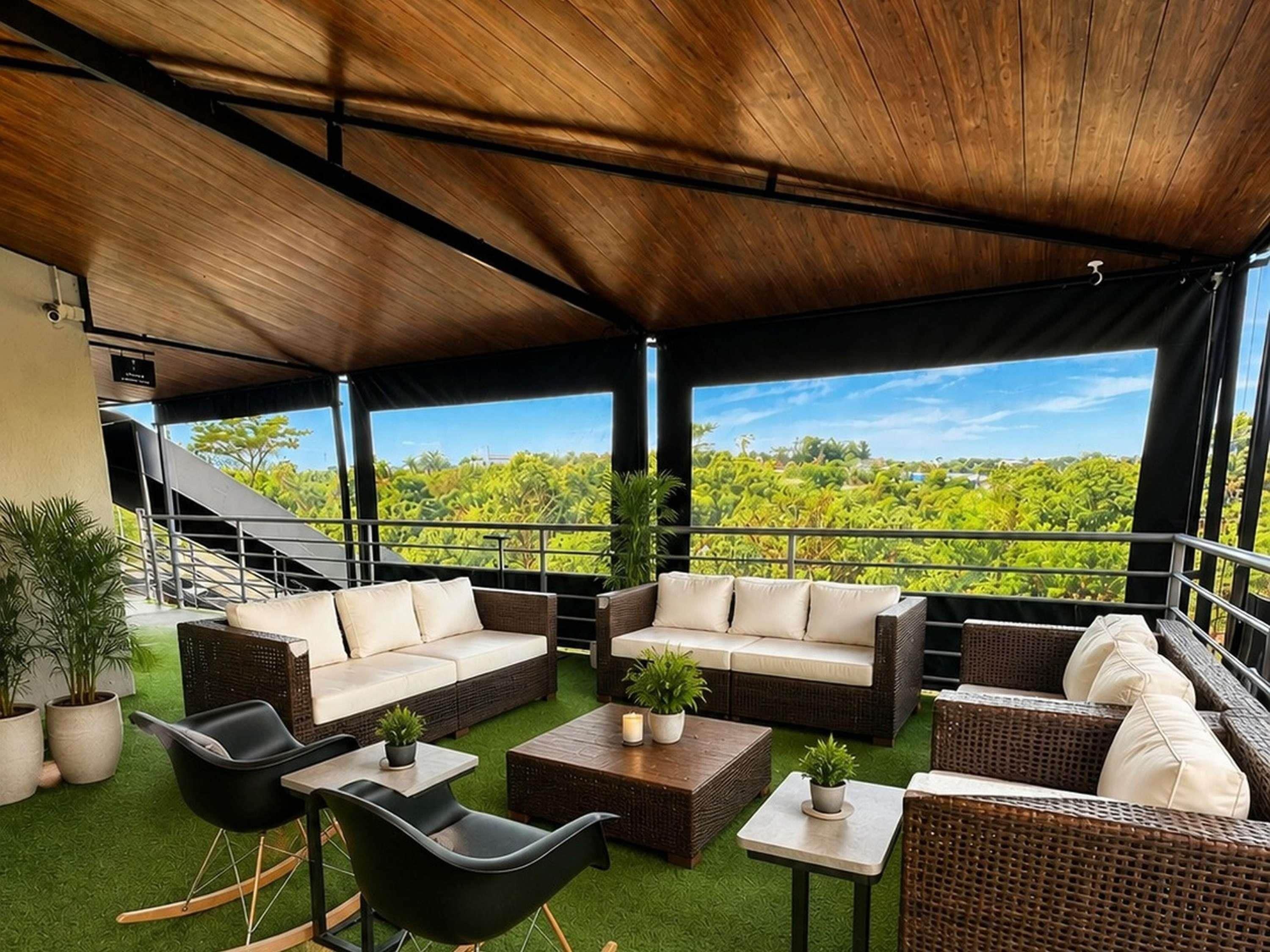 An outdoor seating area with wicker furniture, a green artificial turf floor, and a view of a lush landscape.