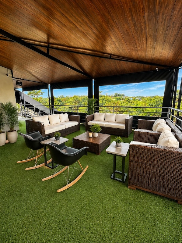 Un área de estar al aire libre con techo y vistas a vegetación exuberante.