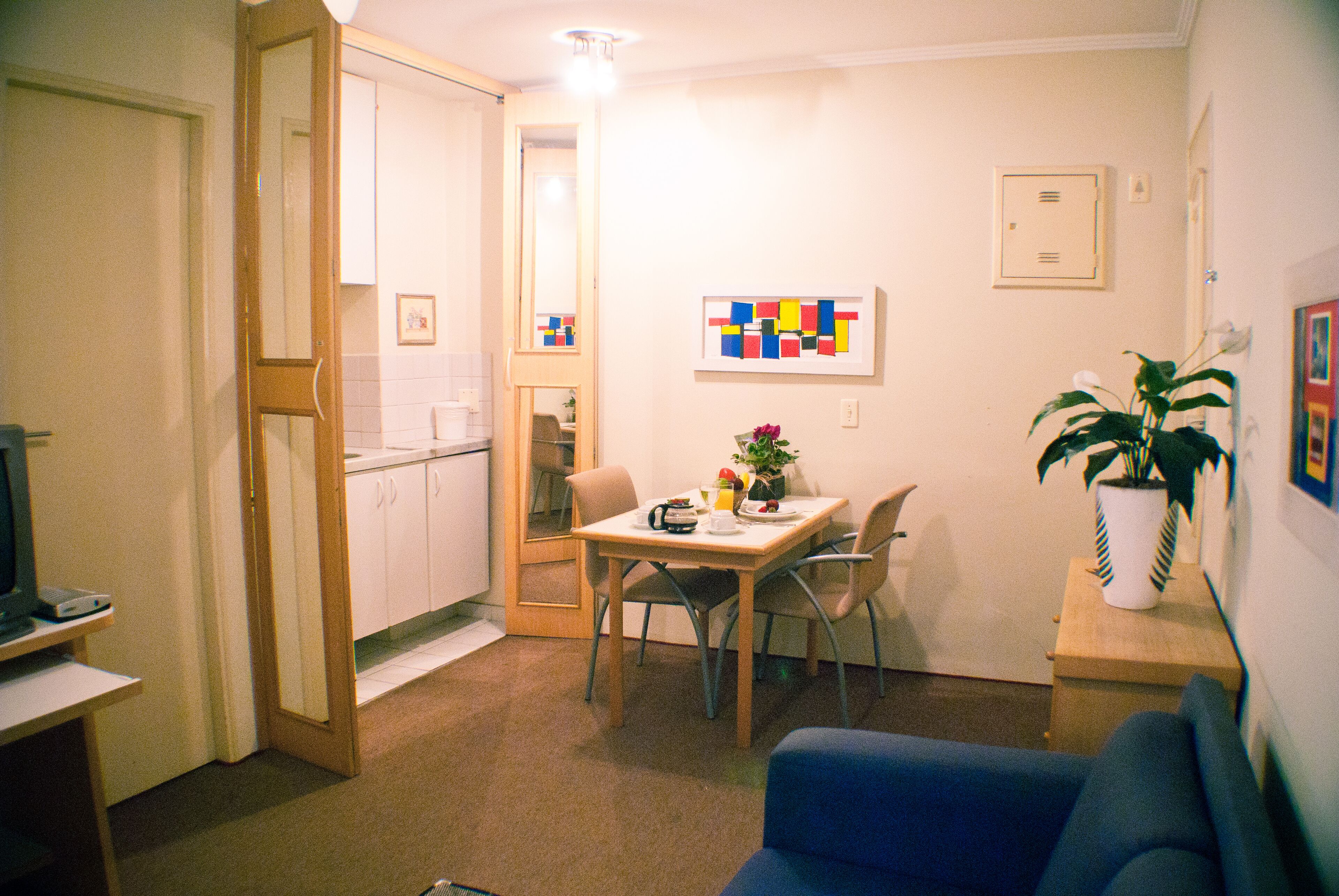 Un espacio habitable compacto con kitchenette, comedor y zona de estar con sofá.