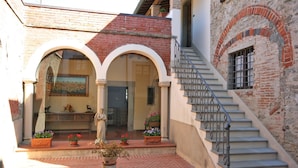 A courtyard with a statue, potted plants, and a staircase leading to an upper level. - Villa Capolona (Capolona)