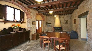A rustic stone kitchen with a large wooden table and chairs, a brick fireplace, and wooden beams on the ceiling. - Villa Capolona (Capolona)