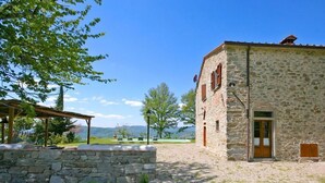 A stone building with a wooden door, a stone wall, and a pergola. - Villa Poggiolino (Subbiano)