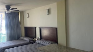 Ein Hotelzimmer mit zwei Betten, einem Deckenventilator, einer Marmorarbeitsplatte und zwei Barhocker.