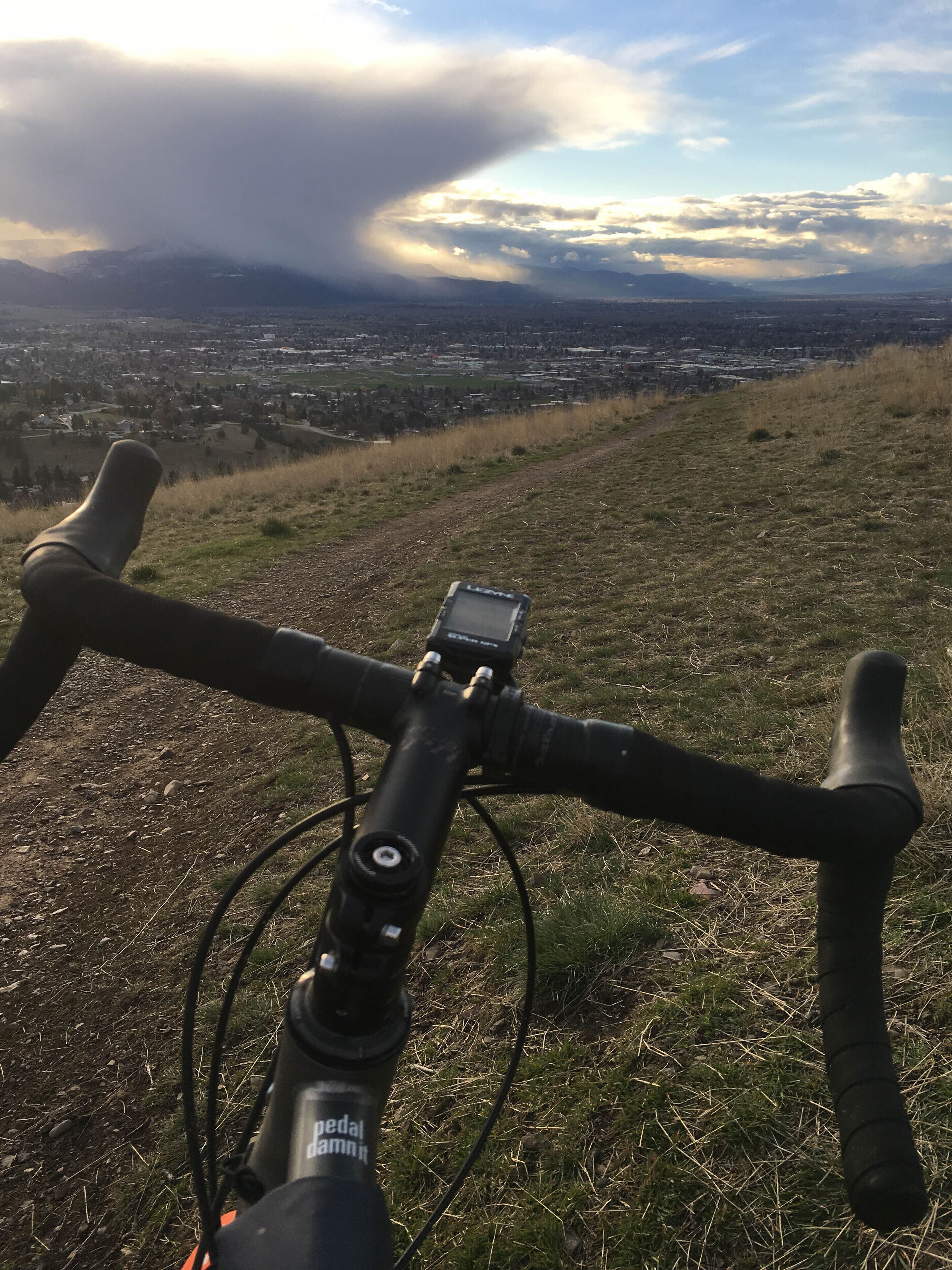Una bicicleta con un dispositivo GPS fijado al manillar, frente a un telón de fondo de paisaje urbano y montañas.