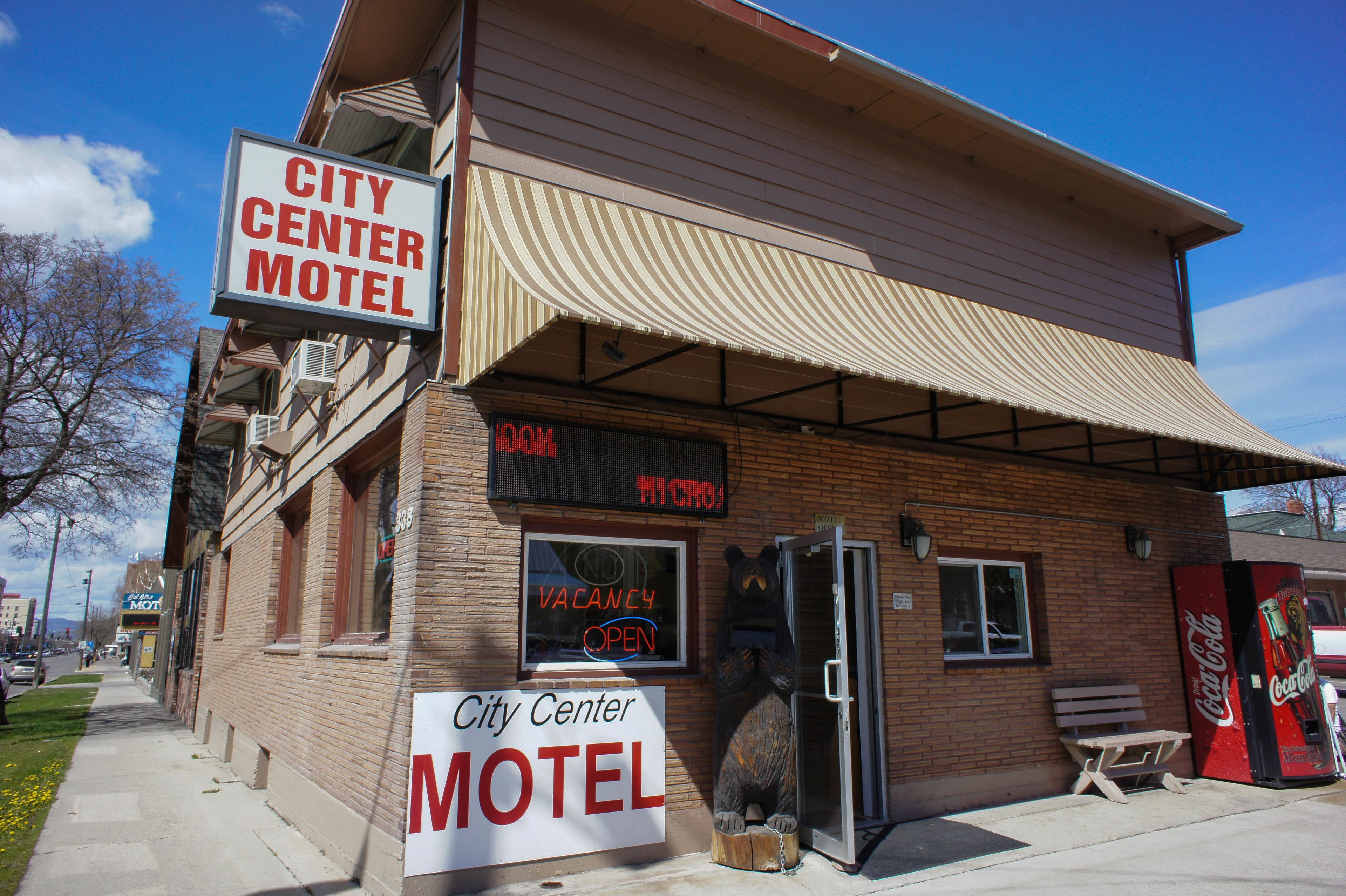 A City Center Motel with a large bear statue outside, a Coca-Cola vending machine, and a sign indicating vacancy.