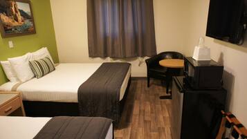 A hotel room with two beds, a desk, a chair, a television, and a refrigerator.