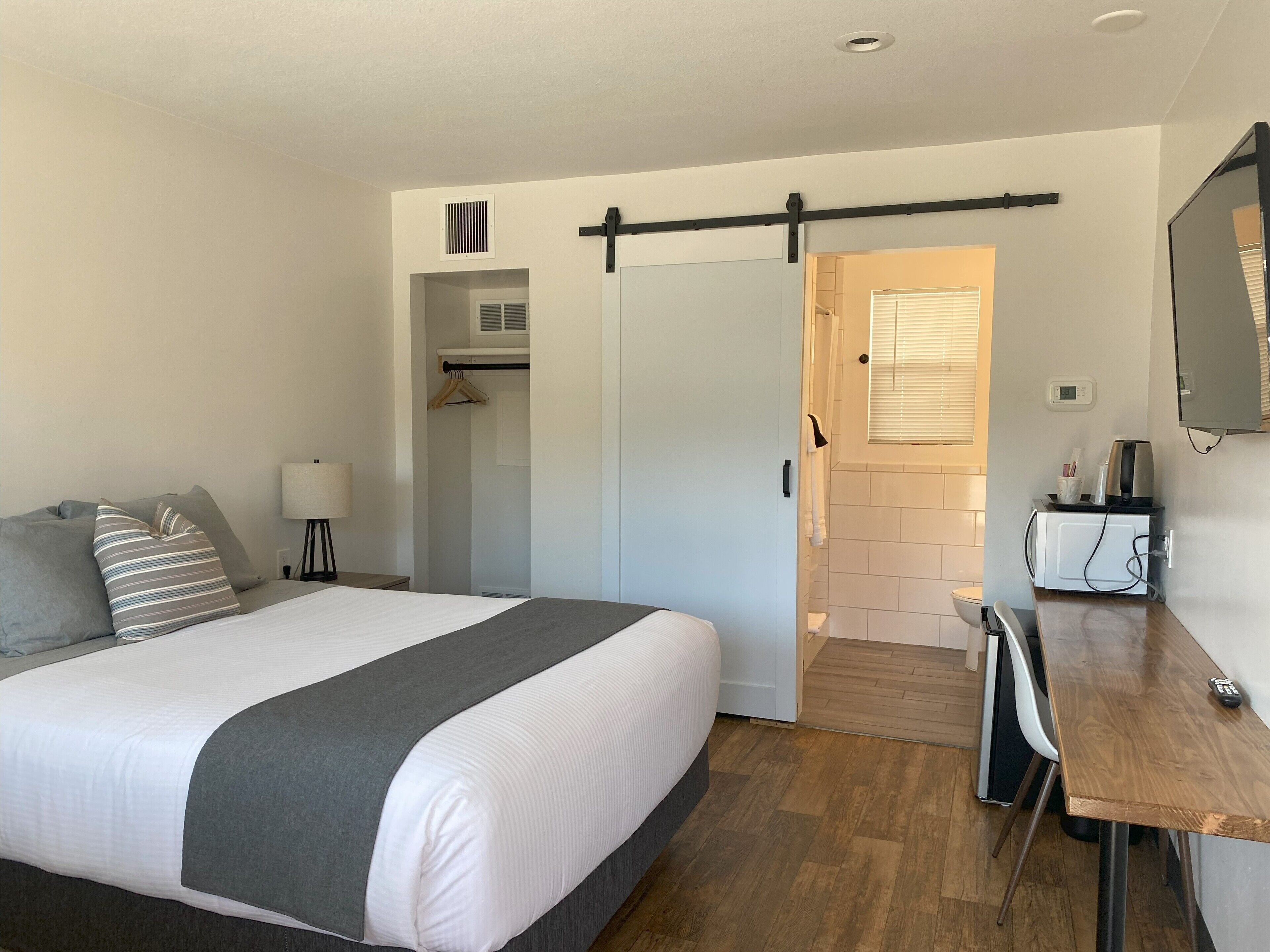 Une chambre d’hôtel moderne dotée d’un grand lit, d’un bureau, d’un miroir et d’une porte coulissante donnant accès à la salle de bain.