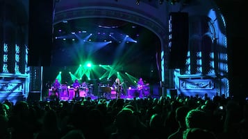 Un escenario de concierto con músicos actuando bajo luces verdes, rodeado de un público.