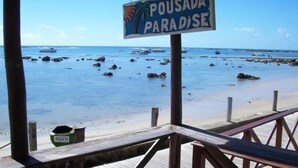 Vista de la playa con un letrero que dice "Pousada Paradise" y una terraza de madera.