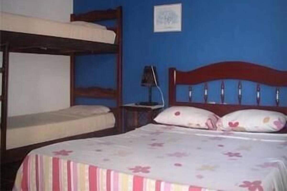 Ein Zimmer mit Etagenbetten, einem Nachttisch mit Lampe und einem gerahmten Bild an der Wand.