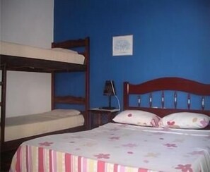Une chambre avec des lits superposés, une table de chevet avec une lampe et un tableau encadré au mur.