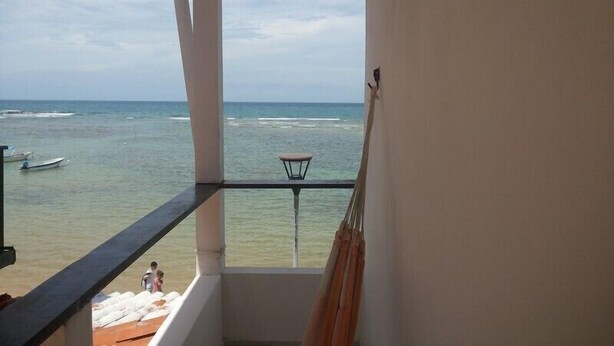 Un balcón con vista al océano, una mesita y una silla.