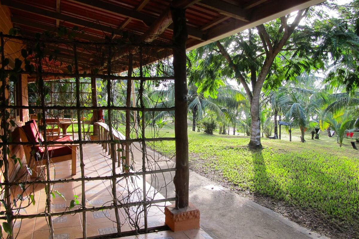 A covered outdoor seating area with a view of a well-maintained lawn and trees.