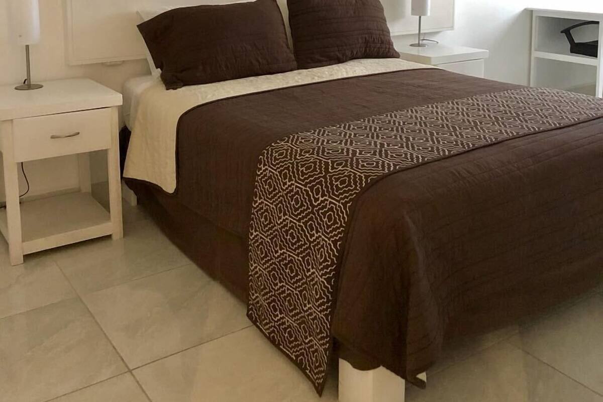 Une chambre à coucher bien rangée, avec un lit, une table de chevet et une lampe.