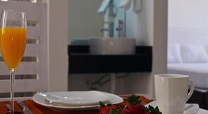 A breakfast setting with a glass of orange juice, a white mug, and a plate with strawberries. - Cantabria House Suites (Aguascalientes)