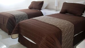 Zwei Betten mit gemusterten Bettdecken in einem Hotelzimmer.