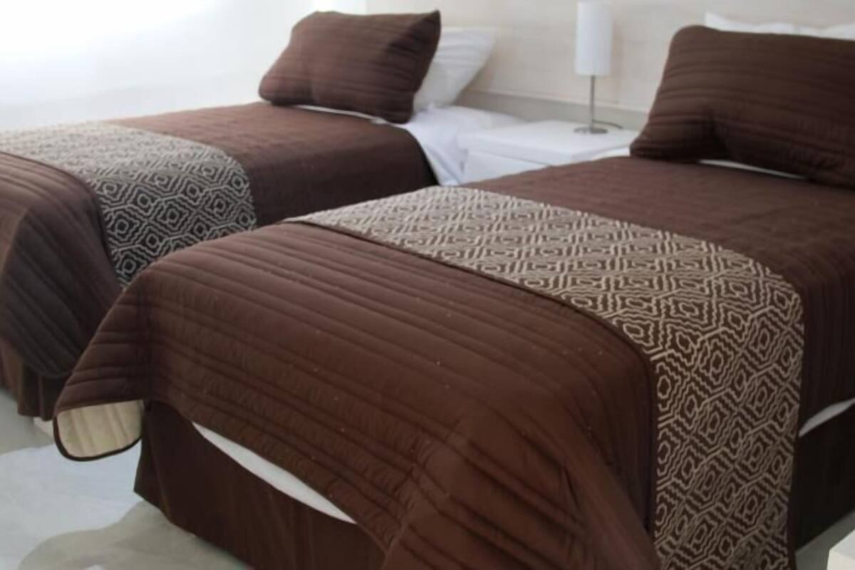 Deux lits avec des couvre-lits à motifs dans une chambre d’hôtel.