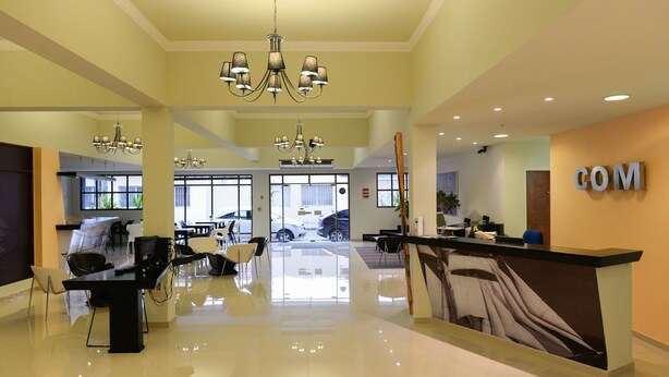 Un moderno vestíbulo de hotel con mostrador de recepción, zona de estar y un candelabro.