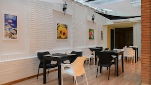 Un comedor moderno con paredes de ladrillo blanco, sillas negras y blancas y obras de arte.