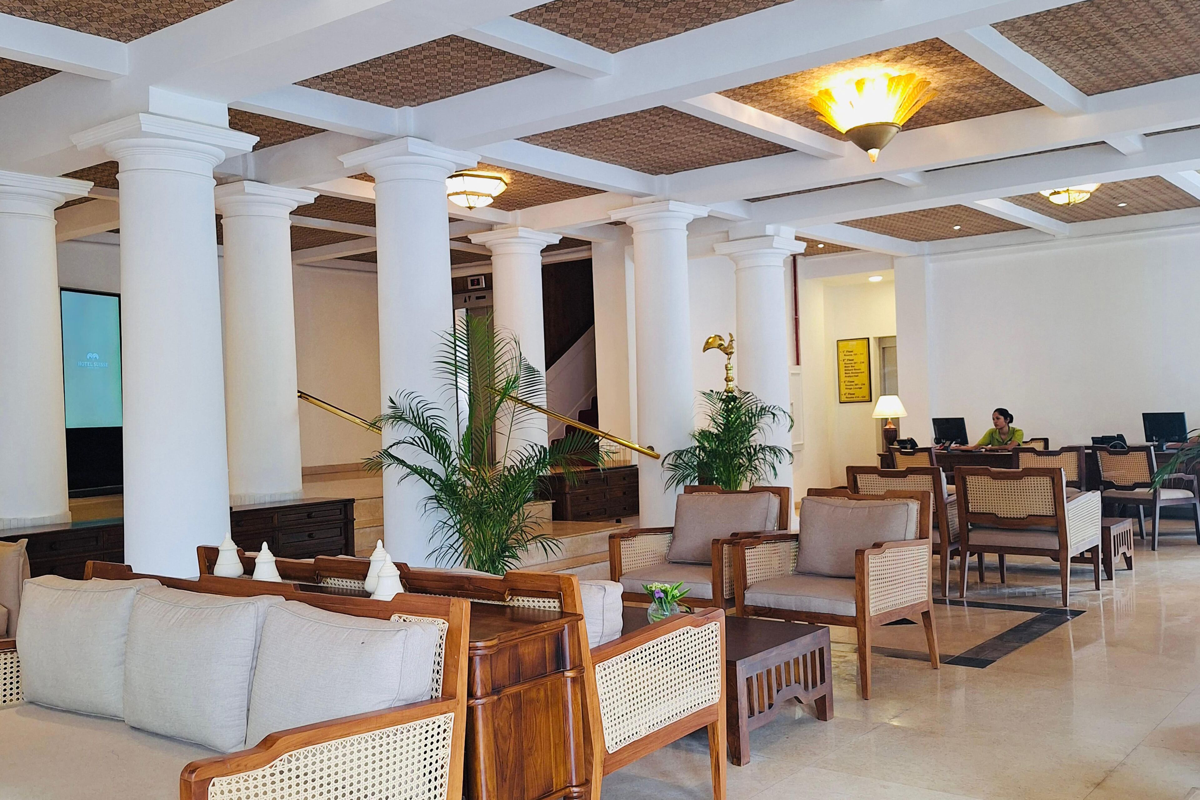 A lobby with wooden furniture, white columns, and a staircase.