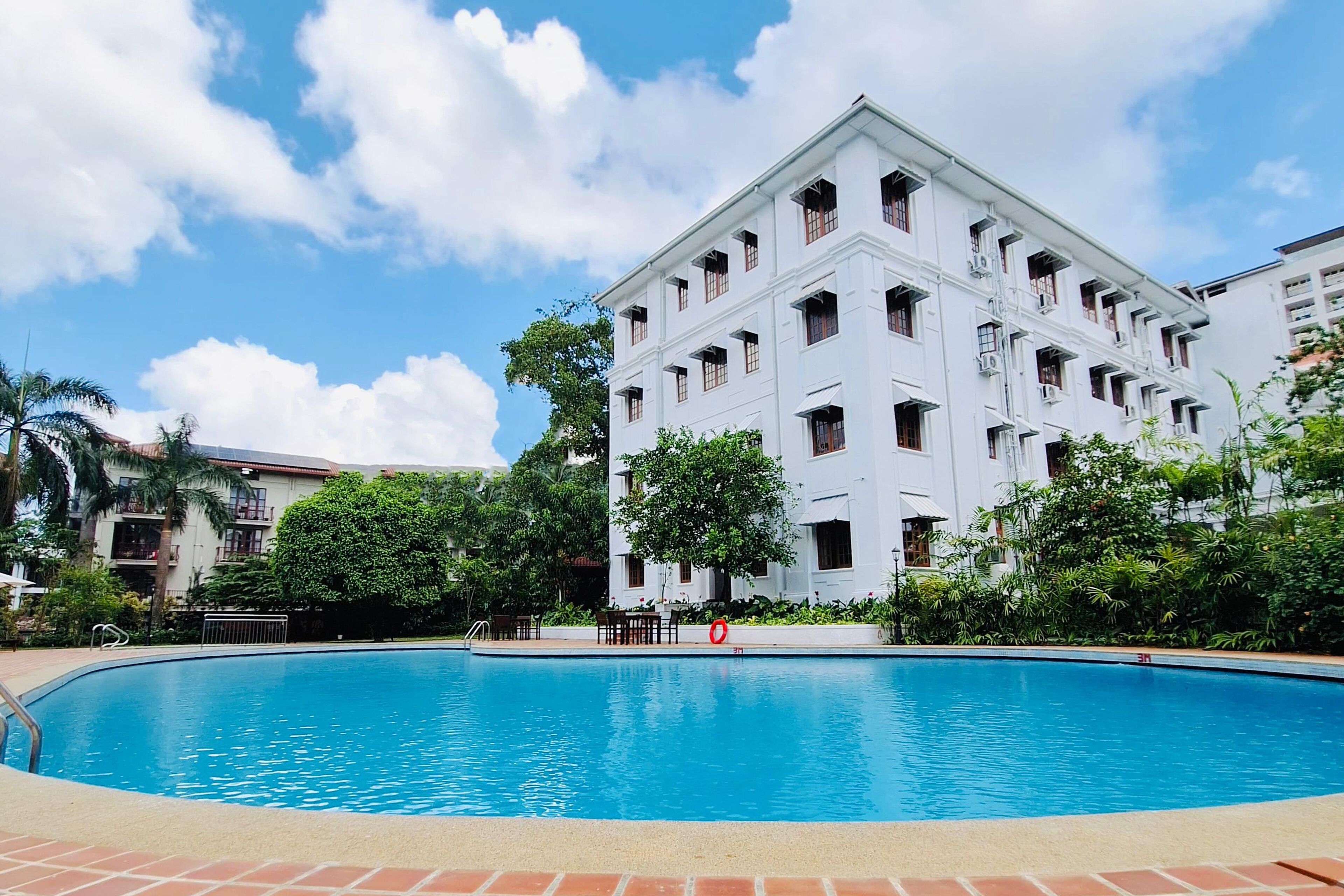 Une grande piscine entourée d’un bâtiment blanc doté de nombreuses fenêtres et de balcons.