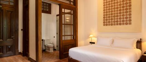 A hotel room with a wooden bed, a large wall-mounted artwork, and a tiled floor.