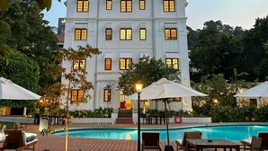 A large building with multiple windows, a swimming pool, and outdoor seating areas. - Hotel Suisse (Kandy)