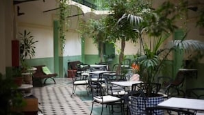 An indoor cafe with tables and chairs, surrounded by potted plants and a tiled floor. - Hotel Peninsular (Barcelona)