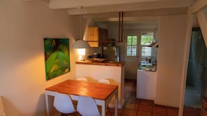Una cucina compatta con zona pranzo, un tavolo di legno e sedie bianche.