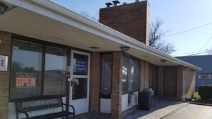 A building with a 'Please Ring Bell' sign, a bench outside, and a 'Yes, We're Open' sign. - Shiva's Travelers Lodge (Niagara Falls)