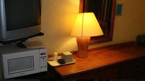 A hotel room with a television, a lamp, a microwave, and a small table with a tray. - Shiva's Travelers Lodge (Niagara Falls)