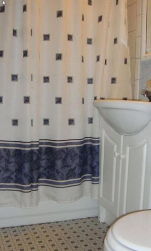 A bathroom with a patterned shower curtain, a white sink, and a tiled floor. - Shiva's Travelers Lodge (Niagara Falls)