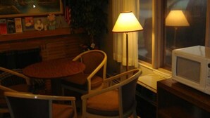 A cozy room with a dining table, two chairs, a lamp, a television, and a microwave. - Shiva's Travelers Lodge (Niagara Falls)