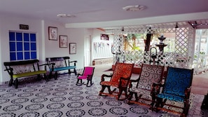 A room with patterned floor tiles, a bench, a rocking chair, and a table with chairs. - Hotel Campestre la Guajira (Santa Marta)