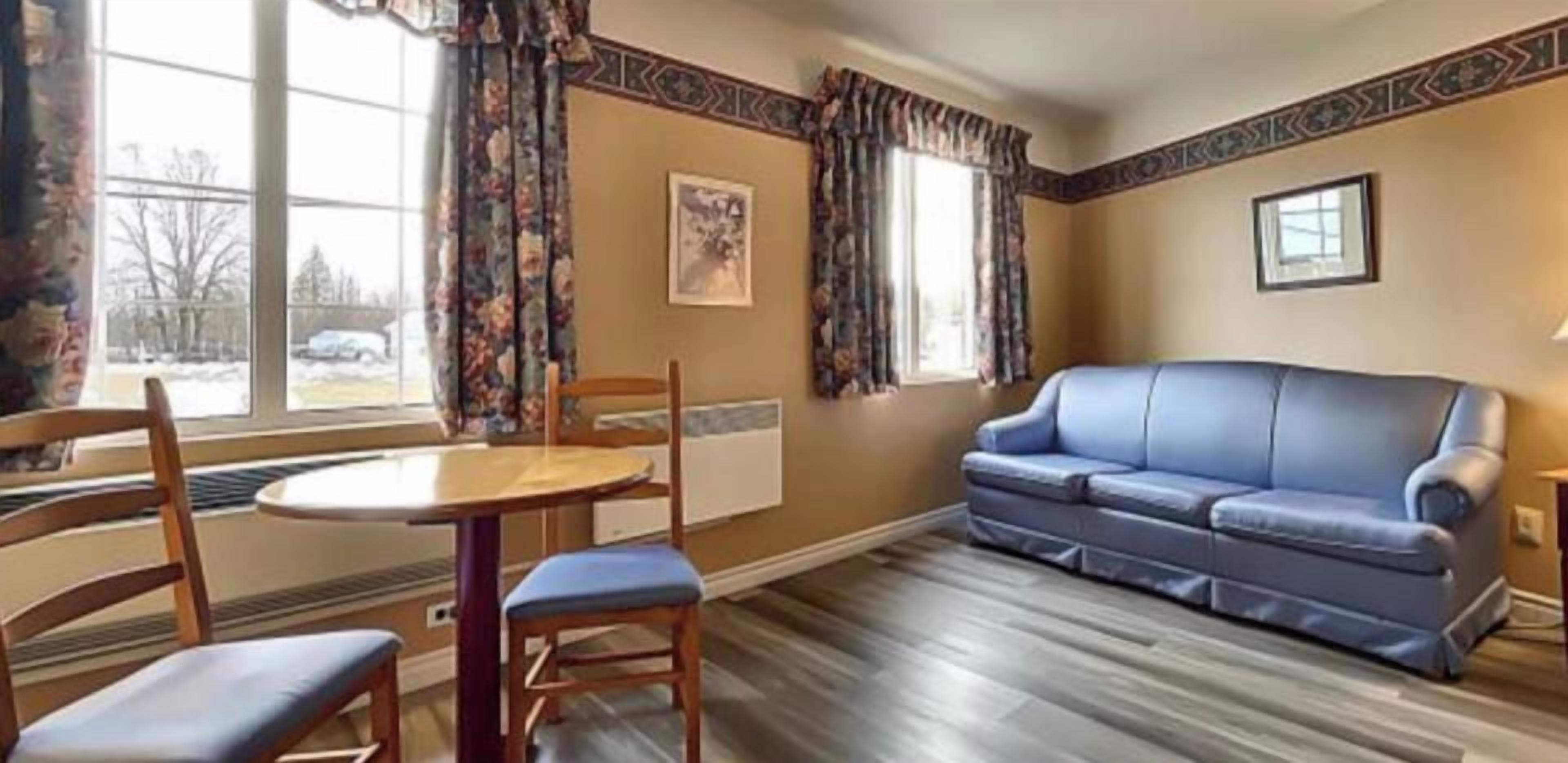 Een kamer met een blauwe bank, een houten tafel en stoelen.