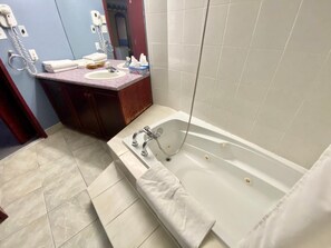 Un baño con bañera, lavamanos y tocador con espejo.