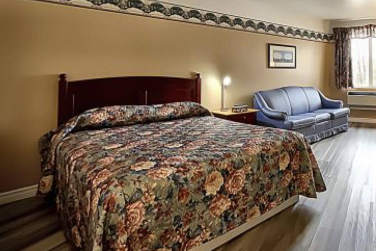 Un dormitorio con una cama grande, un cabecero de madera, un sofá azul y un cuadro enmarcado en la pared.