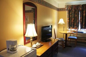 A hotel room with a television, coffee maker, and a dining area with a table and chairs. - Hôtel Le Portneuvois (Portneuf)