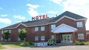 A hotel with a prominent "HOTEL" sign, a brick facade, and a parking lot. - Hôtel Le Portneuvois (Portneuf)